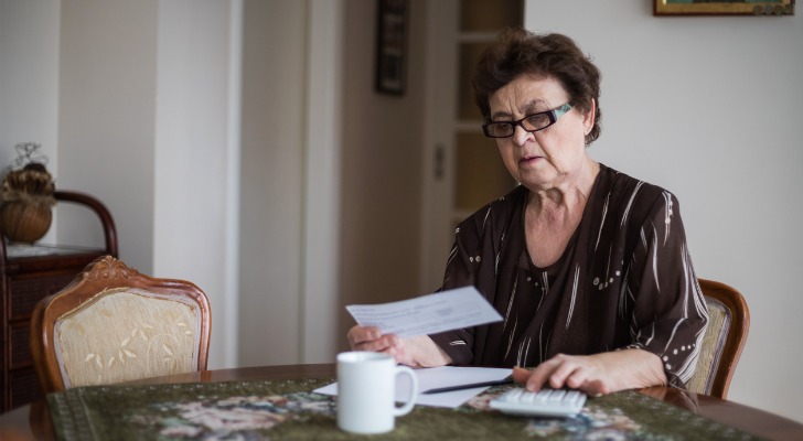 一名妇女在退休后查看自己的账单，但收入很低，无法支付这些账单。